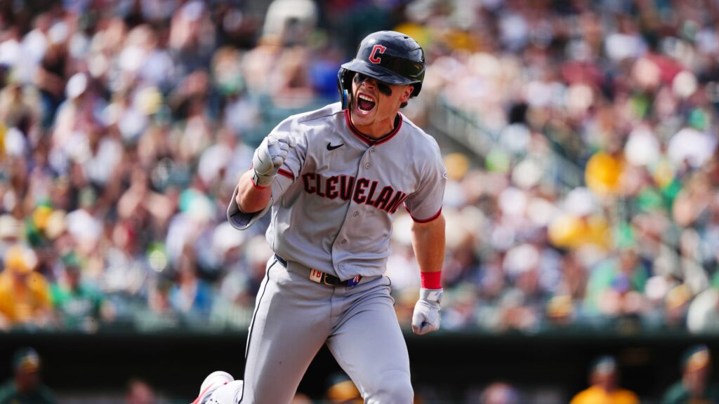 Cleveland Guardians baseball player celebrating on the field, fist raised with a cheering crowd in the background.