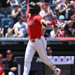 Cleveland Indians batter in a red jersey raises arms in celebration as crowd cheers in the stands.