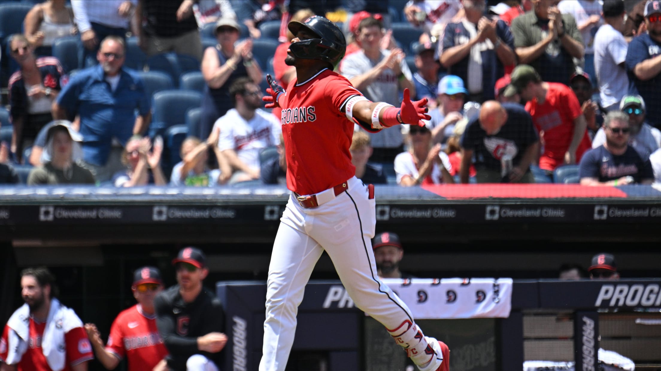 Cleveland Indians batter in a red jersey raises arms in celebration as crowd cheers in the stands.