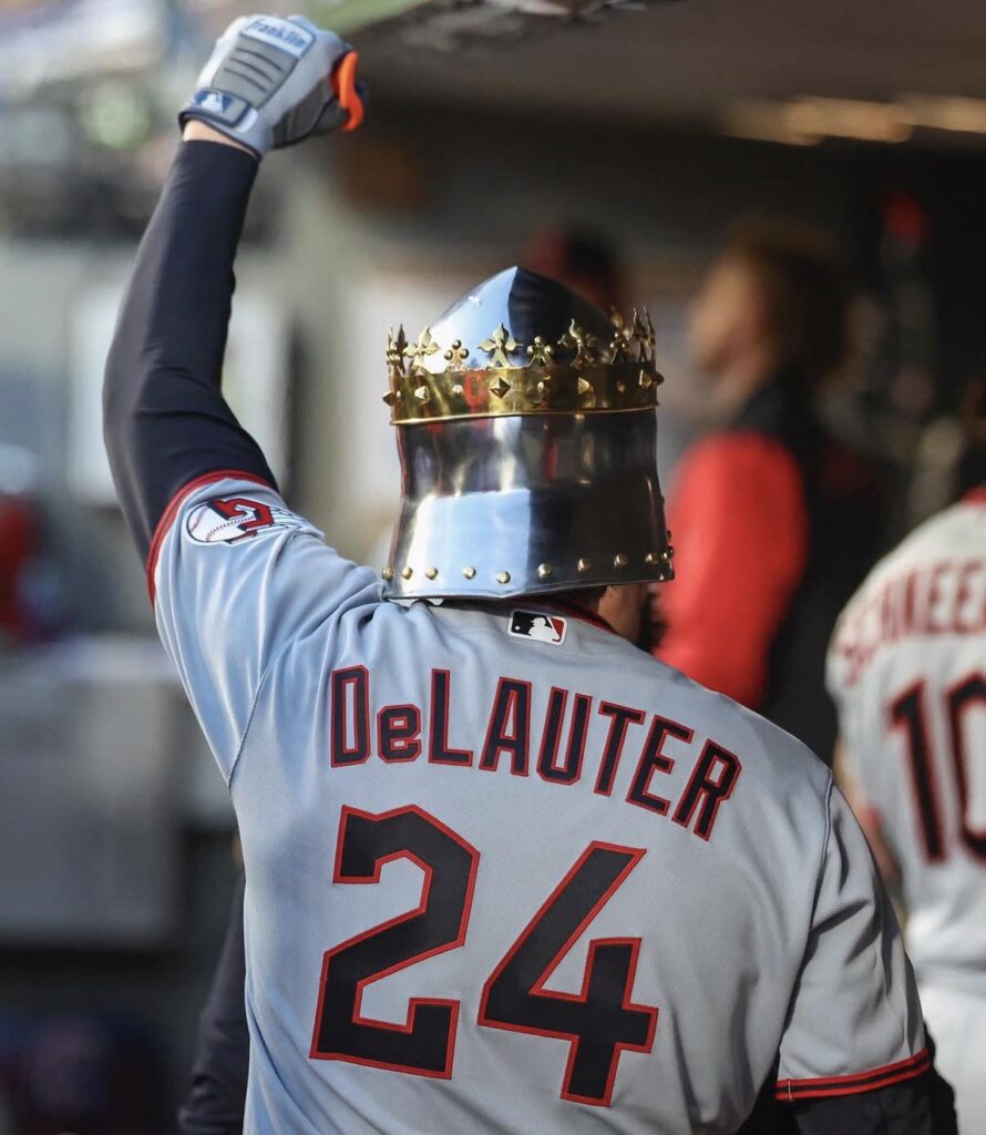 Chase DeLauter wearing a knight’s helmet, raising his fist in victory.